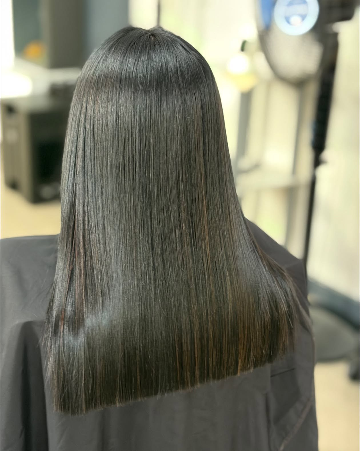 Smooth, glossy dark hair photographed from behind at the salon