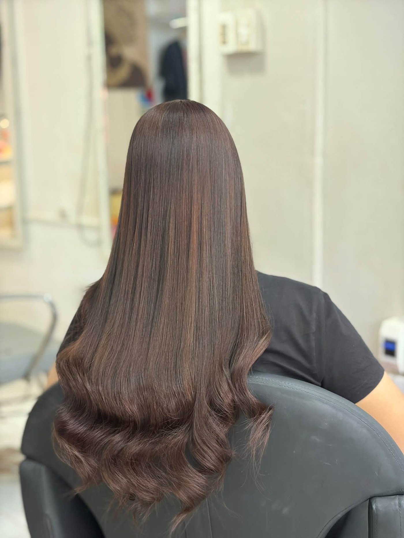 Long brunette hair styled into soft curls, photographed from behind